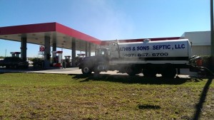 Septic truck providing commercial septic tank cleaning at a property in Orlando, FL with hose connected to tank system.