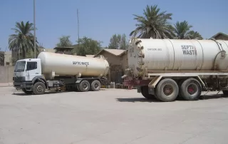 Septic waste trucks stationed outdoors indicating service response to signs of septic system backing up in the area.