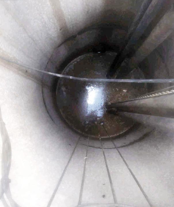 Clean lift station wet well after service, looking down past the guide rails